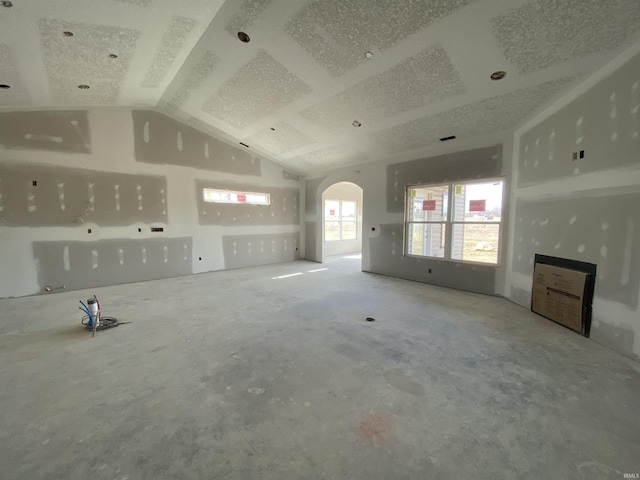 unfurnished living room with arched walkways and lofted ceiling