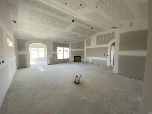 unfurnished living room with arched walkways and lofted ceiling