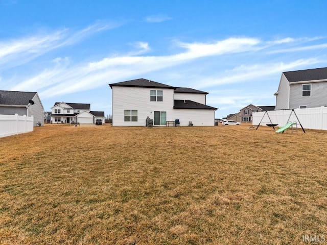 back of property featuring fence and a yard