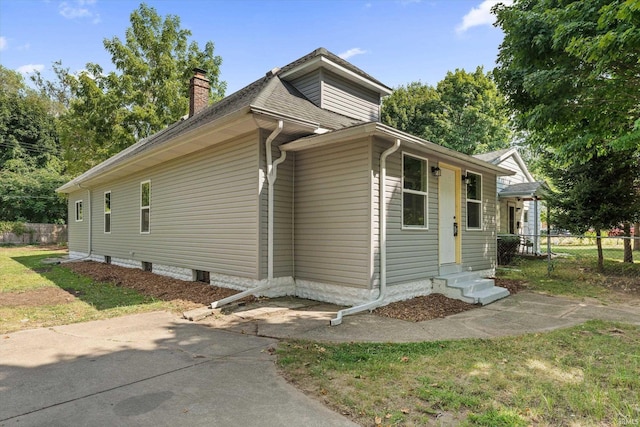 view of home's exterior featuring entry steps, a yard, a chimney, and fence