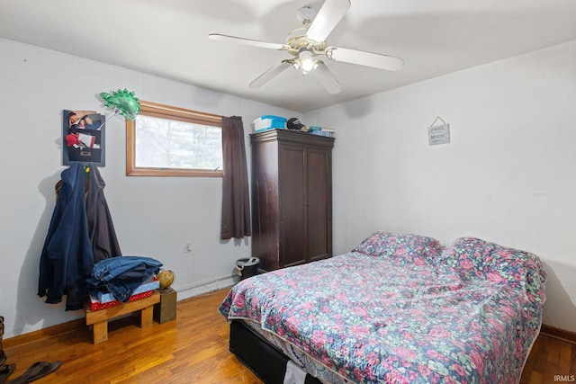 bedroom featuring light wood-type flooring, baseboard heating, and a ceiling fan