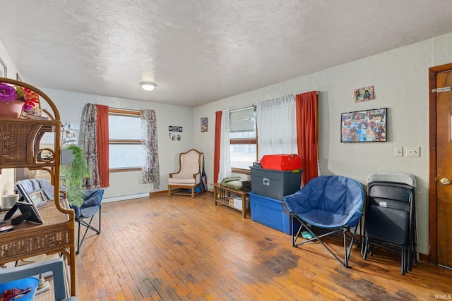 sitting room with a textured ceiling, hardwood / wood-style floors, and baseboards