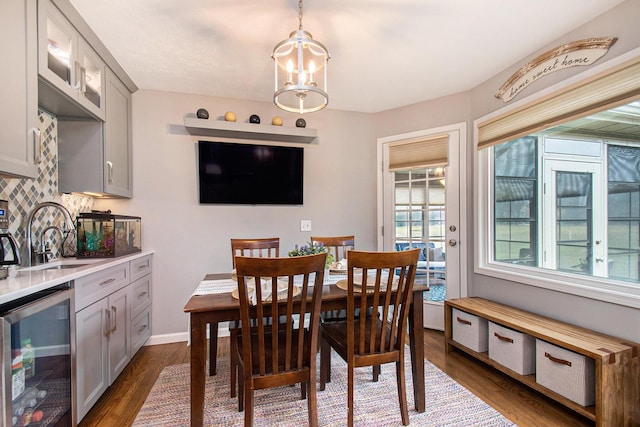 dining area featuring baseboards, wine cooler, dark wood finished floors, and an inviting chandelier