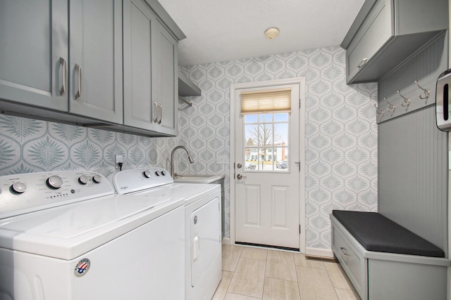 clothes washing area featuring a sink, baseboards, cabinet space, washer and clothes dryer, and wallpapered walls