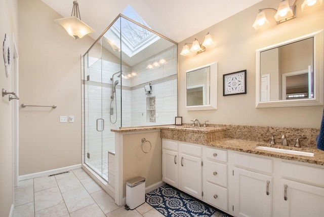 bathroom with double vanity, lofted ceiling with skylight, tile patterned floors, a shower stall, and a sink