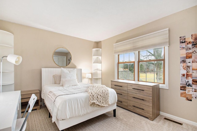 bedroom featuring visible vents, light carpet, and baseboards