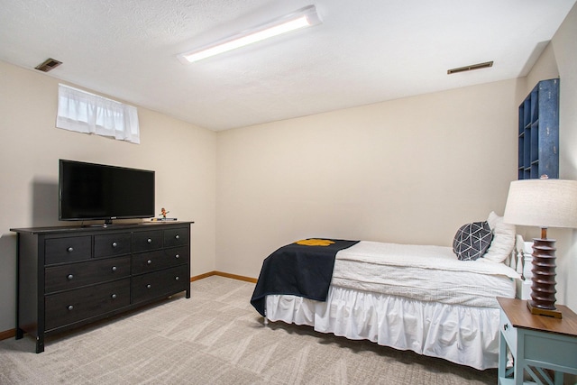 bedroom featuring light carpet, baseboards, visible vents, and a textured ceiling