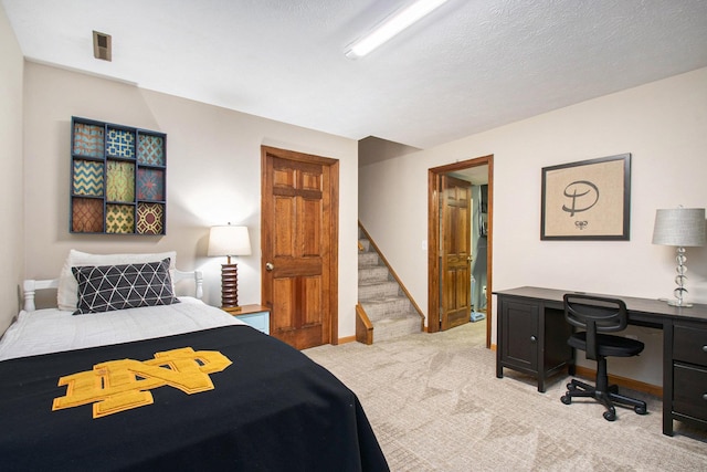 bedroom featuring a textured ceiling, baseboards, and light colored carpet