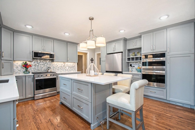 kitchen with appliances with stainless steel finishes, a center island, gray cabinetry, and open shelves