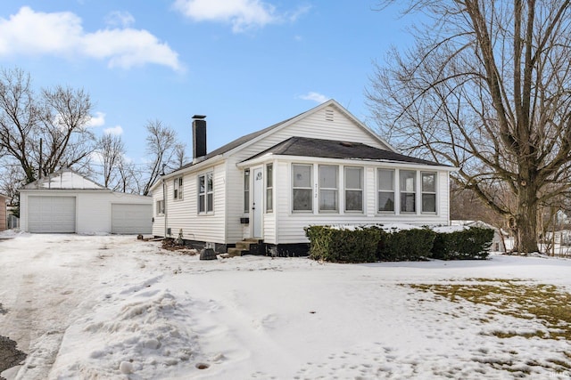 view of front of home with entry steps, a detached garage, a chimney, and an outdoor structure