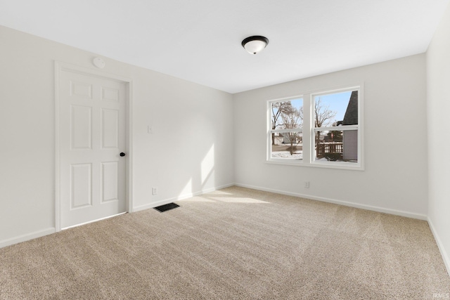 carpeted spare room with visible vents and baseboards