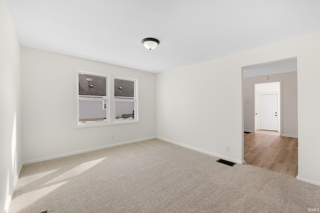 spare room with carpet, visible vents, and baseboards