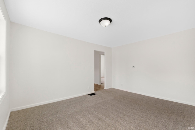 carpeted spare room featuring visible vents and baseboards