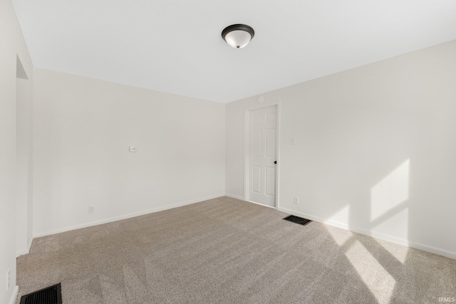 carpeted empty room featuring visible vents and baseboards