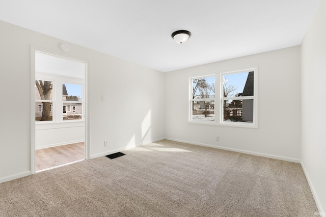 carpeted spare room featuring visible vents and baseboards