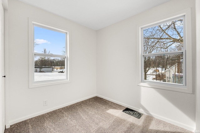 empty room with carpet, visible vents, and baseboards