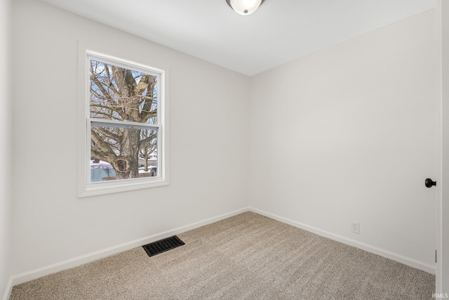 carpeted spare room featuring plenty of natural light, visible vents, and baseboards