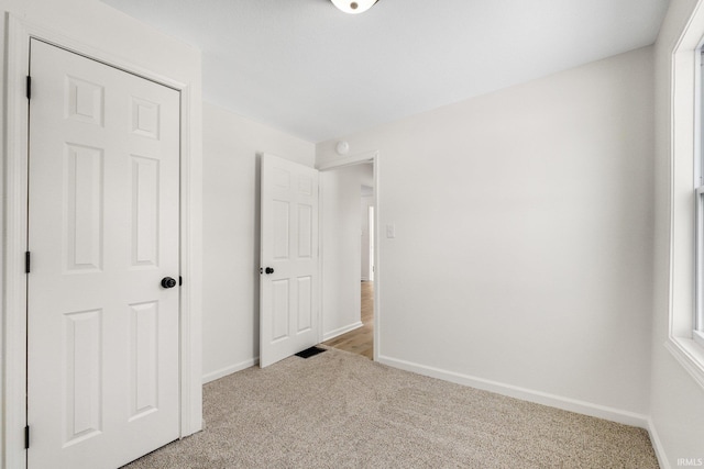 unfurnished bedroom featuring multiple windows, baseboards, and carpet flooring