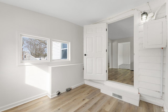 interior space featuring electric panel, visible vents, light wood-style flooring, and baseboards