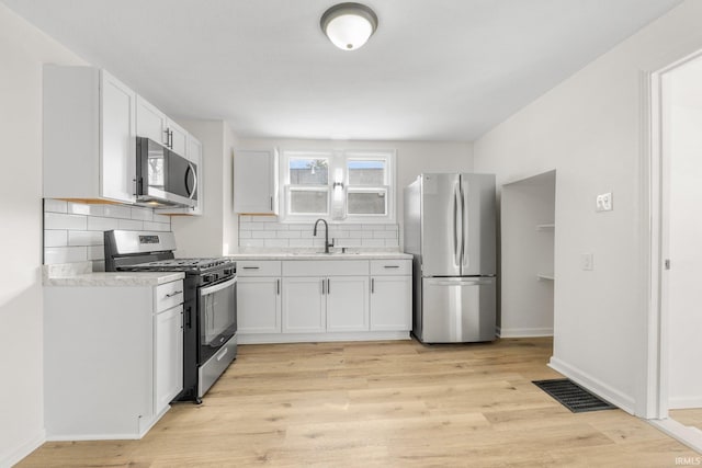 kitchen with light wood finished floors, stainless steel appliances, a sink, and light countertops