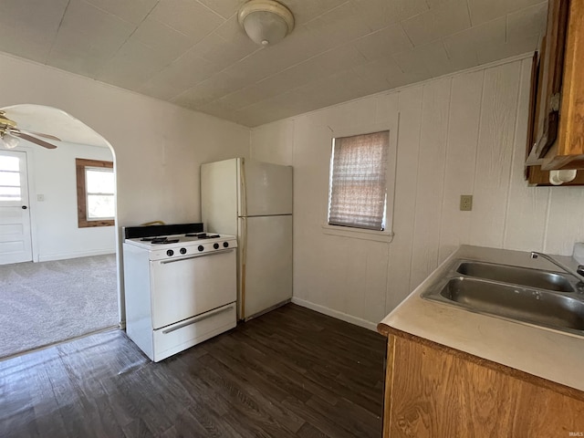 kitchen featuring arched walkways, ceiling fan, white appliances, dark wood-type flooring, and a sink