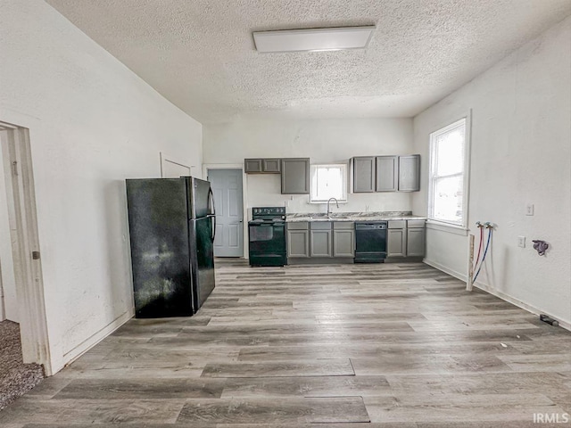 233 W 4th St, Greensburg, IN 47240 - kitchen featuring gray cabinets, light countertops, light wood-type flooring, black appliances, and a sink