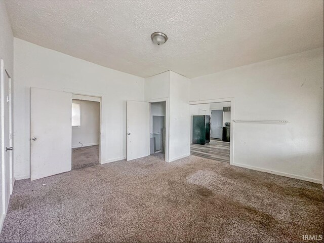 233 W 4th St, Greensburg, IN 47240 - unfurnished bedroom featuring a textured ceiling, baseboards, carpet flooring, and freestanding refrigerator