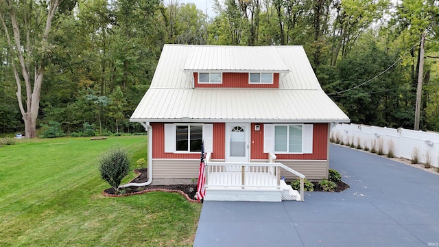 view of front facade featuring metal roof, a front lawn, and fence