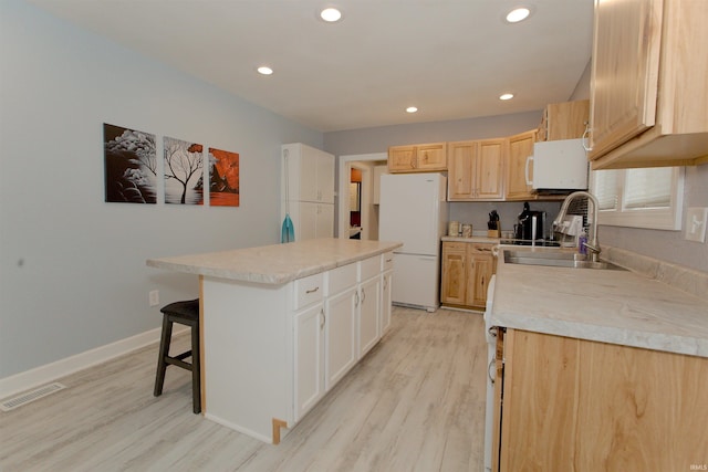 kitchen with light wood-style floors, white appliances, light countertops, and a sink