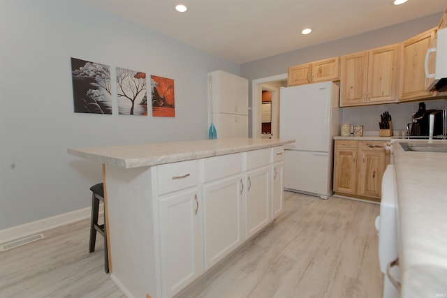 kitchen with white appliances, visible vents, light wood-style floors, light countertops, and a center island