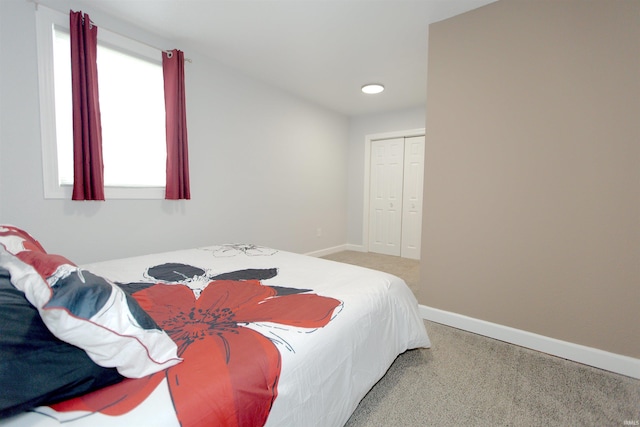 bedroom with light carpet, baseboards, and a closet