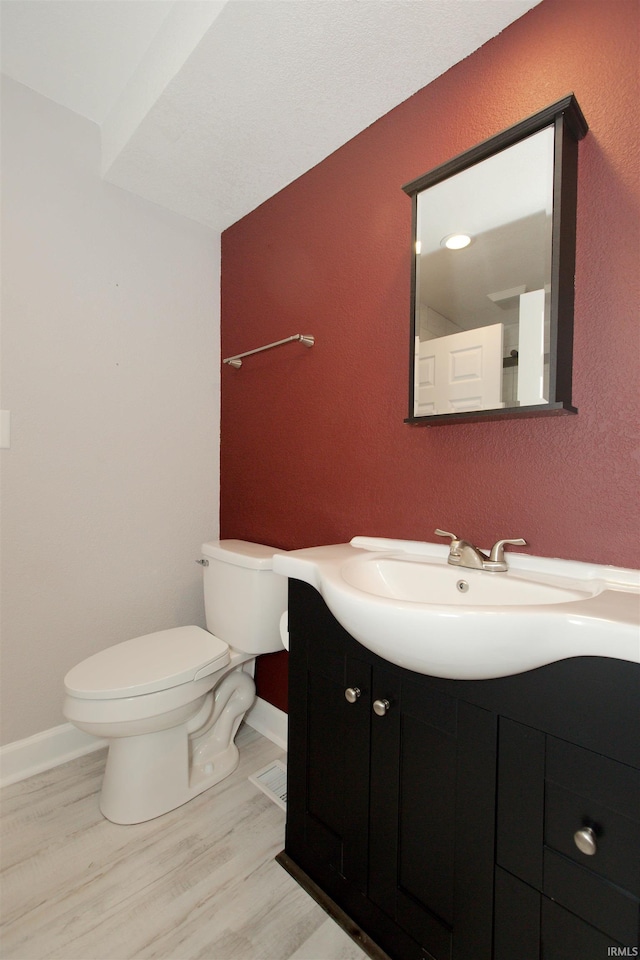 bathroom with baseboards, vanity, toilet, and wood finished floors