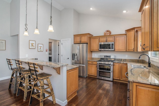 kitchen with stainless steel appliances, a peninsula, a sink, and brown cabinets