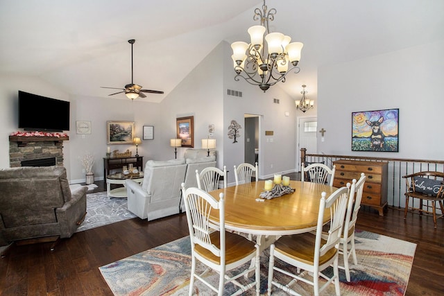 dining area featuring high vaulted ceiling, ceiling fan with notable chandelier, a fireplace, visible vents, and wood-type flooring