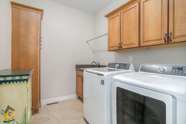 washroom with a sink, visible vents, baseboards, washer and dryer, and cabinet space