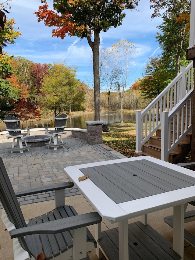 view of patio / terrace featuring an outdoor fire pit, stairway, and a water view