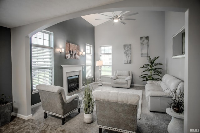 living area featuring baseboards, a glass covered fireplace, and a healthy amount of sunlight