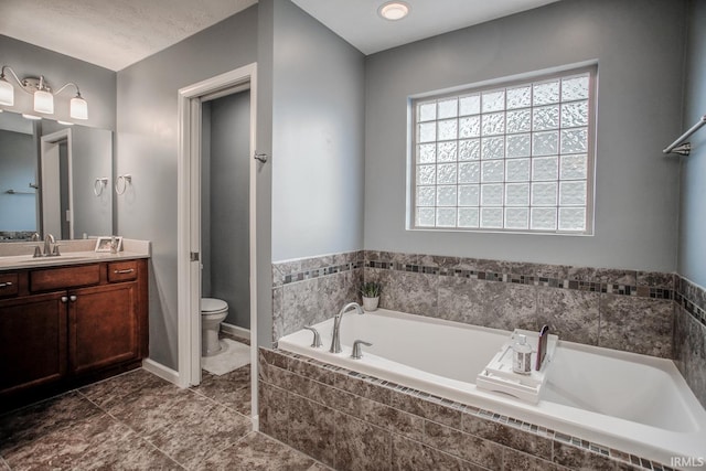 full bathroom featuring a garden tub, toilet, vanity, tile patterned flooring, and baseboards