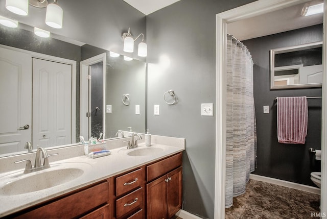 full bath featuring double vanity, baseboards, toilet, and a sink