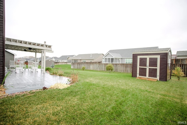 view of yard featuring an outbuilding, a patio, a fenced backyard, a residential view, and a storage unit