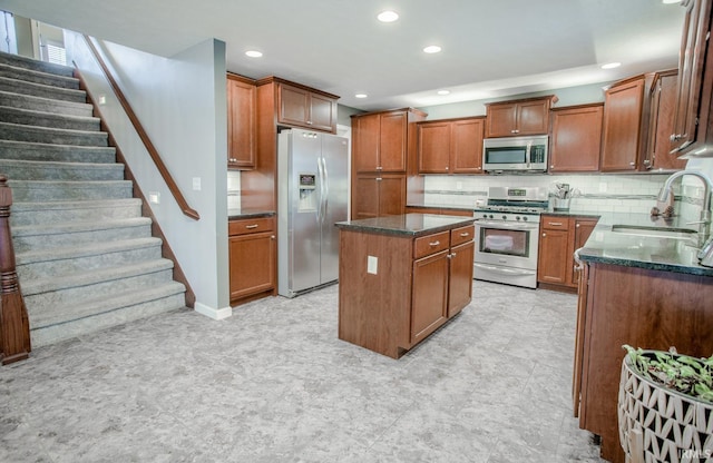 kitchen with decorative backsplash, appliances with stainless steel finishes, a sink, a kitchen island, and dark stone counters