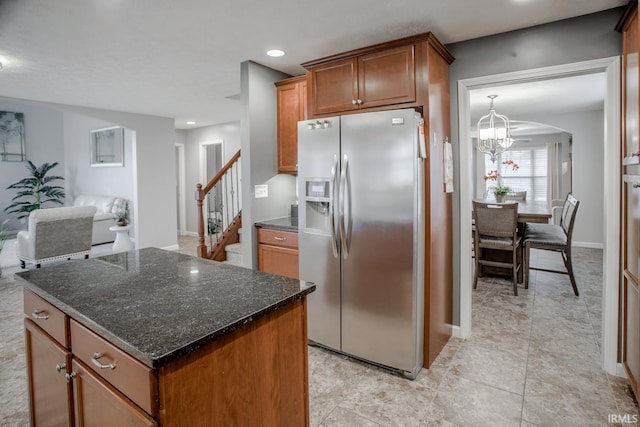 kitchen featuring a notable chandelier, open floor plan, a center island, brown cabinetry, and stainless steel fridge