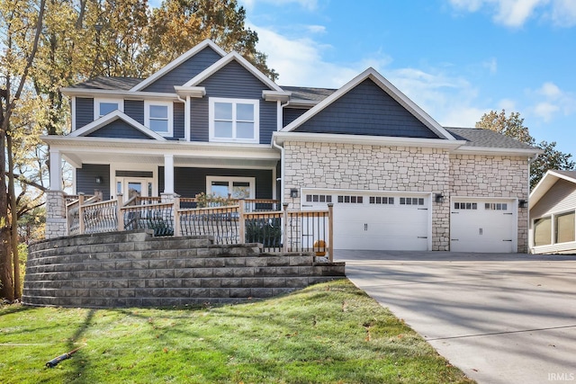 craftsman-style house with a porch, stone siding, driveway, and a garage