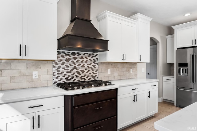 kitchen featuring appliances with stainless steel finishes, custom range hood, backsplash, and white cabinetry