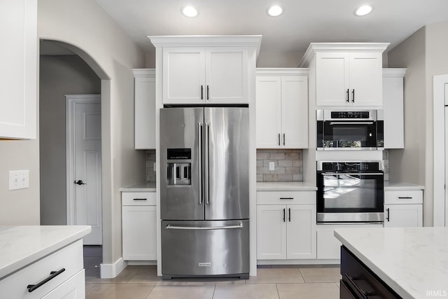 kitchen with tasteful backsplash, appliances with stainless steel finishes, light stone countertops, white cabinetry, and recessed lighting