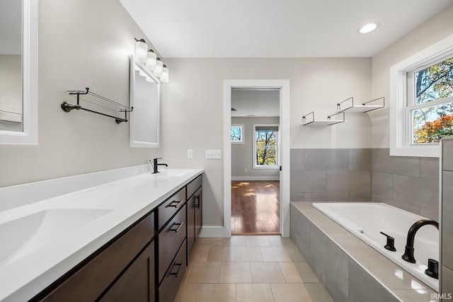 bathroom featuring tiled tub, double vanity, a sink, and tile patterned floors