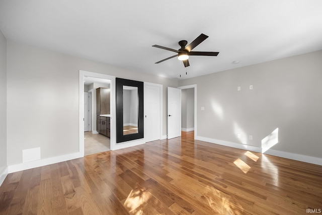 unfurnished bedroom with light wood-style floors, a ceiling fan, baseboards, and ensuite bathroom