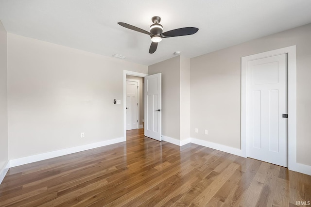 unfurnished bedroom featuring ceiling fan, wood finished floors, visible vents, and baseboards