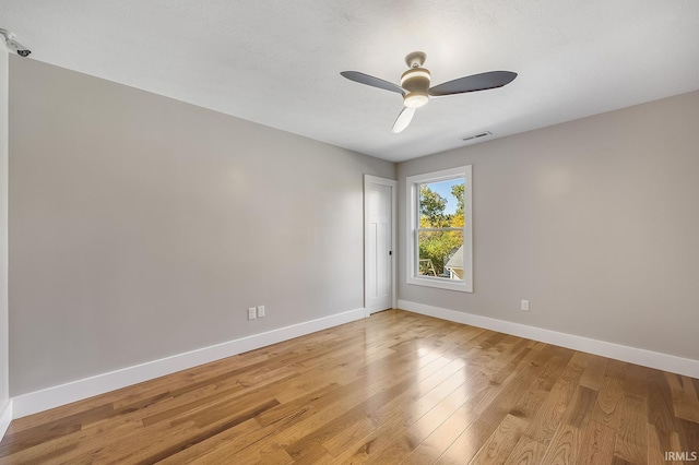 empty room featuring light wood-style floors, visible vents, baseboards, and a ceiling fan