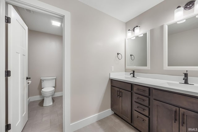 bathroom with double vanity, baseboards, toilet, and a sink